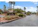 Welcoming entrance to 'The Estates' with lush landscaping, a gated entry, and palm trees against a clear blue sky at 5205 Sandy Cactus Ln, Las Vegas, NV 89149