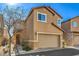 Two-story tan home with a two car garage with minimal landscaping and arched entry way at 6217 Red Jamboree Ct, Las Vegas, NV 89130