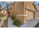 Side view of a two-story tan home with a two car garage and landscaped entry way at 6217 Red Jamboree Ct, Las Vegas, NV 89130