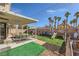 Outdoor area with a covered patio, lush turf, a playset, and mature palm trees at 6982 Rusty Nail Way, Las Vegas, NV 89119