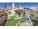 A charming backyard with a covered patio, synthetic grass, and a swing set at 6982 Rusty Nail Way, Las Vegas, NV 89119