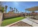 Wide backyard with a grill, seating, brick walls, lush artificial turf, and tall palm trees at 6982 Rusty Nail Way, Las Vegas, NV 89119