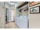 A bright laundry room with tile flooring, washer, dryer, and shelving at 6982 Rusty Nail Way, Las Vegas, NV 89119
