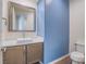 Powder room with wood cabinets, white countertop and sink plus modern fixtures and blue accent wall at 816 Stannard Ct, Henderson, NV 89052