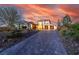 Elegant two-story home with a paver driveway and beautiful landscaping at sunset at 18 Grand Corniche Dr, Henderson, NV 89011
