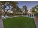 Expansive backyard with artificial turf, mature trees, and serene seating area, ideal for outdoor leisure at 1900 Vero Dr, Las Vegas, NV 89134