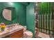 Stylish bathroom with a sleek vanity, round mirror, toilet, and shower with unique green vertical tiling at 1900 Vero Dr, Las Vegas, NV 89134