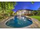 Stunning backyard pool with spa, framed by lush landscaping and an inviting patio area at twilight at 1900 Vero Dr, Las Vegas, NV 89134