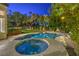 Backyard pool and spa with lush landscaping, lighting, and ample space for entertaining and relaxation at 1900 Vero Dr, Las Vegas, NV 89134