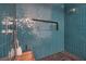 Walk-in shower showcasing unique teal tile, pebble flooring, and a built-in toiletry shelf at 1900 Vero Dr, Las Vegas, NV 89134