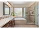 Luxurious bathroom with a soaking tub, glass-enclosed shower, and double vanity at 2279 Pacini Ct, Henderson, NV 89052