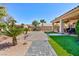 Wide backyard showcasing brick pathway, desert landscaping, patio, and putting green at 3662 Riley Ann Ave, Las Vegas, NV 89139