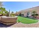 An expansive backyard with a putting green, mature landscaping, and covered patio at 3662 Riley Ann Ave, Las Vegas, NV 89139