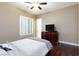 Cozy bedroom features dark wood floors and plantation shutters, with a TV on a dresser at 3662 Riley Ann Ave, Las Vegas, NV 89139