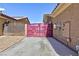 A property side yard showcasing a unique pink metal gate and concrete pathway at 3662 Riley Ann Ave, Las Vegas, NV 89139