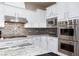 Close up of modern kitchen with stone backsplash, stainless appliances and white cabinetry at 3662 Riley Ann Ave, Las Vegas, NV 89139