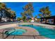 Community pool and hot tub with blue tiled accents surrounded by lounge chairs and mature landscaping at 3667 Edinburgh Dr, Las Vegas, NV 89103