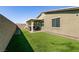 Backyard with artificial turf, covered patio with seating, and a privacy wall, perfect for outdoor entertaining at 4227 Diya Ave, North Las Vegas, NV 89084