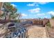 A mostly empty backyard with a partial fence, an American flag, a grill, and some immature trees at 4655 Fire Fly Cir, Las Vegas, NV 89122