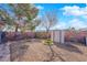 Gravel backyard featuring a storage shed and some immature trees within a brick-walled yard at 4655 Fire Fly Cir, Las Vegas, NV 89122