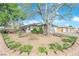 Single-story home featuring stone accents, an attached garage, desert landscaping, and a large shade tree in the front yard at 4655 Fire Fly Cir, Las Vegas, NV 89122