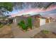 Single-story home with a stone accent wall, attached garage, concrete driveway, and desert landscaping beneath a colorful sunset sky at 4655 Fire Fly Cir, Las Vegas, NV 89122