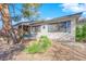 Single-story home with desert landscaping, bench, and mature tree at 4655 Fire Fly Cir, Las Vegas, NV 89122