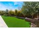 Lush backyard with manicured artificial grass, mature trees, and retaining walls, offering a private outdoor retreat at 5027 Crown Cypress St, Las Vegas, NV 89149