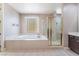 Well lit bathroom featuring a soaking tub, glass shower, and neutral tile at 5027 Crown Cypress St, Las Vegas, NV 89149