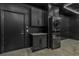 Modern laundry room featuring sleek black cabinetry, granite counters, and a stacked washer and dryer at 600 N Carriage Hill Dr # 1164, Las Vegas, NV 89138