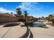 A backyard oasis with a freeform pool, mature palm trees, and rock features at 78 Siddall Ave, Las Vegas, NV 89183