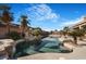 Backyard pool with palm trees, rock waterfall feature, and nearby covered patio at 78 Siddall Ave, Las Vegas, NV 89183