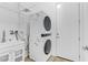 Functional laundry room featuring a stacked washer and dryer, utility sink, and shelving for storage at 783 Hibiscuss Blossom St, Henderson, NV 89011