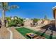 Fenced backyard with an entertainment area that includes corn hole setup, mature trees and desert landscaping at 97 Zimmerman St, Henderson, NV 89002