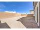 Backyard with sandy surface, brick walls, and blue sky with white clouds at 1027 Gentle Swan St # 689, Henderson, NV 89011