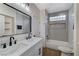 Bright bathroom featuring a double vanity with modern black fixtures and a tiled shower-tub combo with stylish glass block window at 1317 Fox Acres Dr, Las Vegas, NV 89134