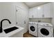 Functional laundry room with sink, white cabinets, and modern washer and dryer at 1317 Fox Acres Dr, Las Vegas, NV 89134