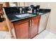 A cozy kitchenette with a stainless steel sink, dark countertop, and wood cabinetry at 145 Harmon Ave # 1021, Las Vegas, NV 89109