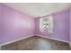 This bedroom has purple walls, wood-look floors, and a window with bars at 1520 Teton St, Las Vegas, NV 89101
