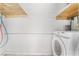 A close-up of the laundry room area with a newer washing machine and wood shelving above at 1520 Teton St, Las Vegas, NV 89101