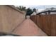 Long driveway along the side of the house with brick pavers and wood fencing on a cloudy day at 1910 Hoover St, North Las Vegas, NV 89030