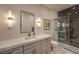 Modern bathroom featuring a marble countertop, gray cabinets, decorative wall sconces and a glass shower with marble tile at 1912 Glenview Dr, Las Vegas, NV 89134