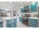 Bright kitchen with blue lower cabinets, white countertops, stainless steel appliances and large window at 2540 Hummingbird Hill Ave, Henderson, NV 89074