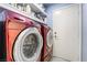 Modern laundry room featuring red front-loading washer and dryer and convenient overhead shelving at 2540 Hummingbird Hill Ave, Henderson, NV 89074