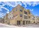 Three-story building featuring multiple garages, neutral stucco exterior, and tile roof with a sunny, clear sky at 2555 Hampton Rd # 4204, Henderson, NV 89052