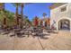Inviting patio with several tables and chairs, shaded by red umbrellas and surrounded by greenery at 2555 Hampton Rd # 4204, Henderson, NV 89052