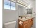 Well-lit bathroom featuring a wood vanity, large mirror, and a frosted glass window at 2628 Showcase Dr, Las Vegas, NV 89134