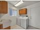 Functional laundry room with wooden cabinets, a utility sink, and a washer and dryer at 2628 Showcase Dr, Las Vegas, NV 89134