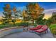 Outdoor living with custom patio seating, chairs, and green golf course views beyond the wrought iron fence at 2872 Sumter Valley Cir, Henderson, NV 89052
