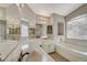 Bathroom with dual sinks, large mirrors, a bathtub, and neutral tile flooring at 3417 Steppe St, North Las Vegas, NV 89032